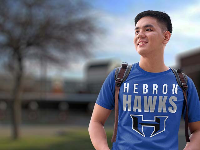 Person wearing a blue 'Hebron Hawks' t-shirt with a blurred background