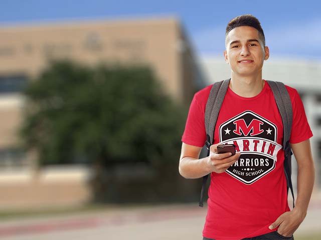Young man wearing a red Martin Warriors t-shirt with a blurred school building in the background