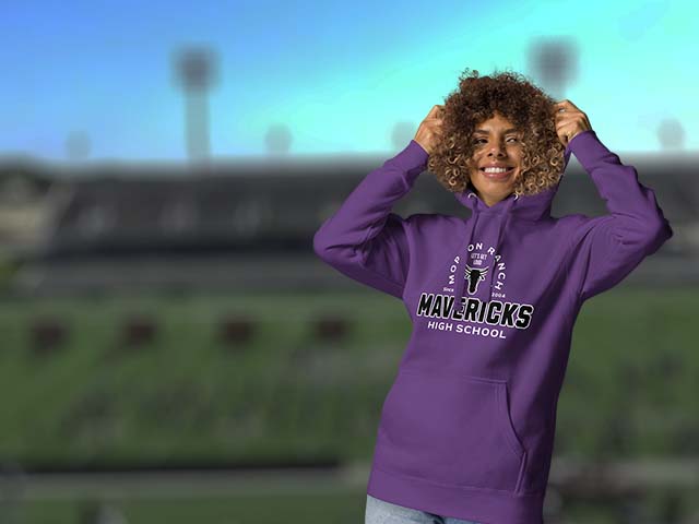 Person wearing a purple hoodie with 'Mavericks High School' text, standing on a sports field.