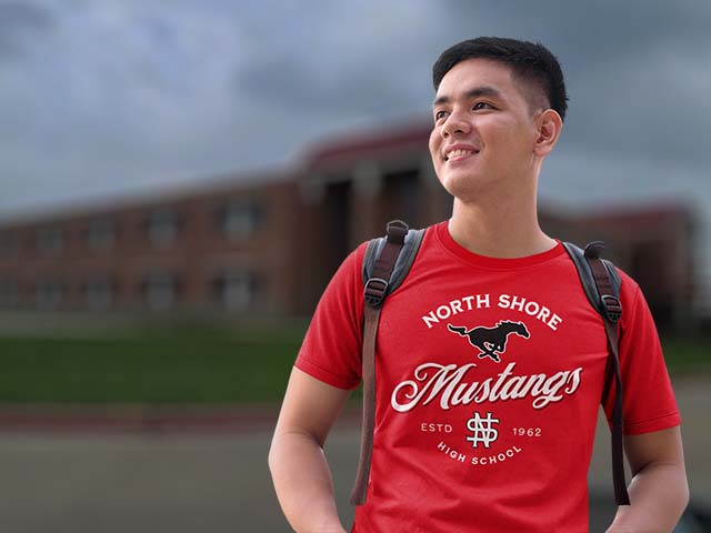 Person wearing a red 'North Shore Mustangs' t-shirt with a school building in the background