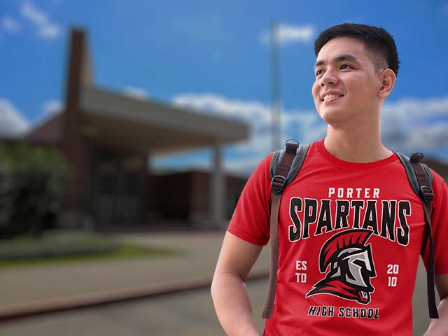 Person wearing a red 'Porter Spartans' t-shirt with a school building in the background