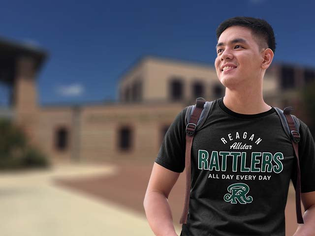 Person wearing a black t-shirt with 'Reagan Allstar Rattlers' text and logo, standing outdoors.