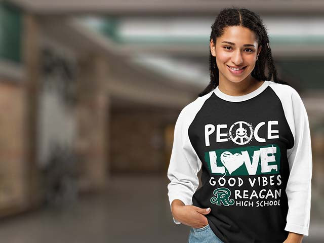 Person wearing a black and white sweatshirt with 'Peace Love Good Vibes Reagan High School' text.