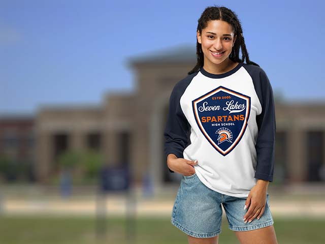 Girl wearing a Seven Lakes High School Raglan T-shirt standing in front of the school. Go Spartans!