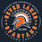 A circular graphic design featuring an orange and white Spartan helmet logo in the center, surrounded by the words 'SEVEN LAKES SPARTANS' in orange and white, with 'Unleash the Champion Within' and 'Est 2005' text on a dark navy background. Seven Lakes High School Spartans Women's Navy Blue SoftStyle T-shirt 214