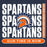 A dark navy graphic design featuring the word 'SPARTANS' repeated in large distressed white letters, with a central Spartan helmet logo in orange, navy, and white. A vertical orange strip on the right reads 'SEVEN LAKES HIGH SCHOOL,' and an orange rounded bar at the bottom reads 'OUR TIME IS NOW. Seven Lakes High School Spartans Unisex 3/4 sleeve Raglan T-shirt 235