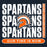 A graphic design featuring the word 'SPARTANS' repeated vertically in large distressed white letters, with a central Spartan helmet logo in orange, white, and black. A vertical orange label on the right reads 'SEVEN LAKES HIGH SCHOOL,' and an orange rounded bar at the bottom reads 'OUR TIME IS NOW. Seven Lakes High School Spartans Women's Navy Blue SoftStyle T-shirt 235
