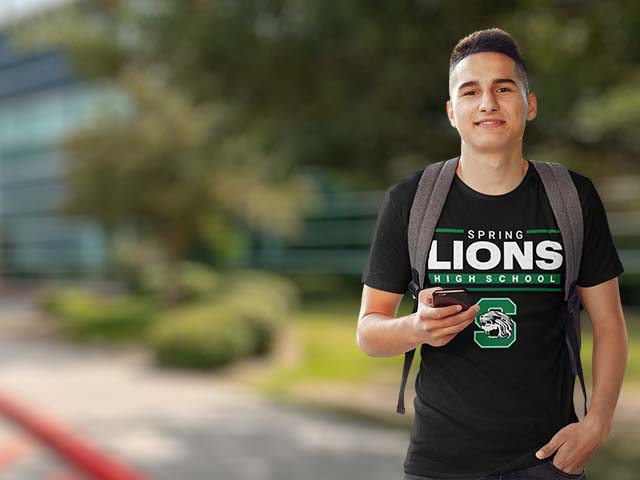 A young man wearing a black t-shirt with 'SPRING LIONS HIGH SCHOOL' and a green 'S' logo printed on the front, standing outdoors with a blurred background.