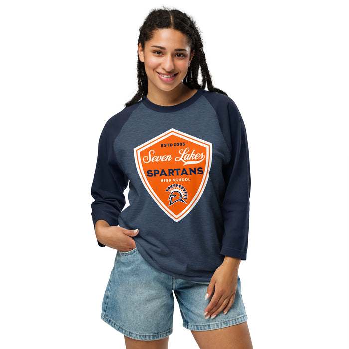 A woman modeling a navy blue 3/4 sleeve raglan t-shirt with a large orange and white shield graphic on the front that reads 'Seven Lakes Spartans High School'. She is wearing light-wash denim shorts against a solid white background. Seven Lakes High School Spartans Unisex 3/4 sleeve Raglan T-shirt 225